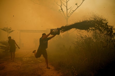 A resident pours water to extinguish a wildfire near a residential area in Banyuasin, South Sumatra province, Indonesia