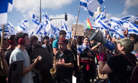 Protestors wave flags as thousands of Israelis attend a rally against Israeli Government's judicial overhaul plan on March 27, 2023 in Jerusalem.