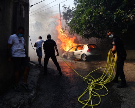 Car on fire, plumes of smoke and officers with hose