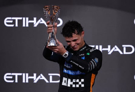 McLaren’s Lando Norris celebrates on the podium with the trophy after becoming the 2025 Formula One world champion