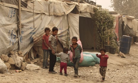 Syrian refugees stand outside tents at a camp in Bar Elias, Lebanon