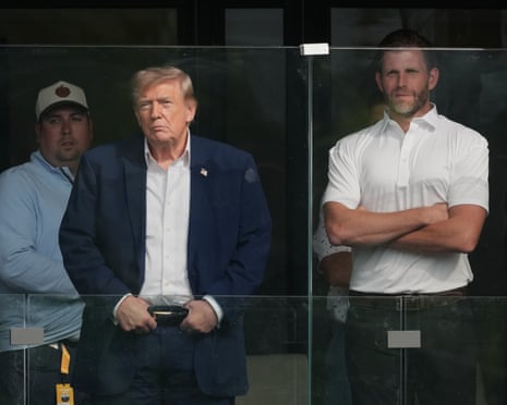 Two men standing beside each other look in the same direction behind glass.