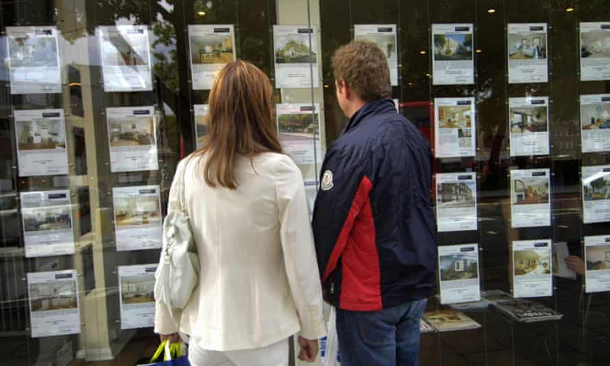 A couple standing outside an estate agent’s window.