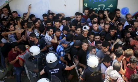 Migrants and refugees are hemmed in by riot police at a stadium on Kos on 12 August.