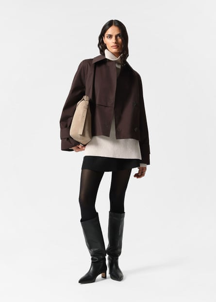 A model wearing a dark brown cropped trench coat and black mini skirt