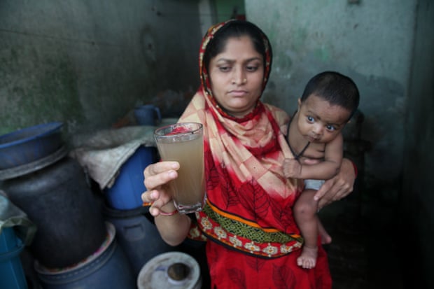 A Bangladeshi woman holds a glass of contaminated water in Dhaka.