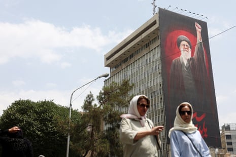 People walk near a billboard depicting Iran