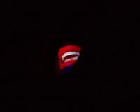 Claire Booth as Mouth in Not I, a spotlit mouth glowing in darkness