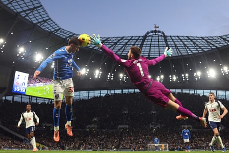 Trai Hume of Sunderland heads the ball as goalkeeper Guglielmo Vicario of Tottenham dives to save.