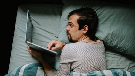 A man lying successful furniture looking astatine a laptop