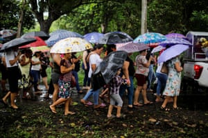 Mourners holding umbrellas at a funeral