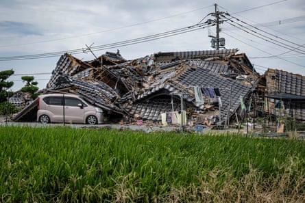 A house is seen collapsed onto a car in Hikawa.