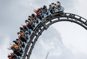 People ride a rollercoaster against a cloudy sky