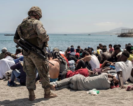 A soldier watches over people on a beach