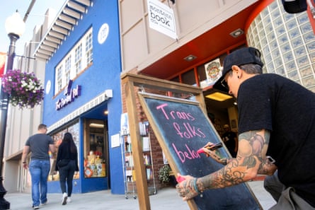 Charlie Crawford writes “trans folks belong in Montana” on the sandwich board outside their bookstore.