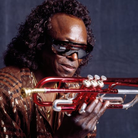 Miles with long hair, holding red and silver trumpet