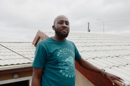 A man stands resting his arm on the tiles of a roof