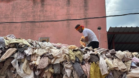 A man stands on a pile of clothing outside