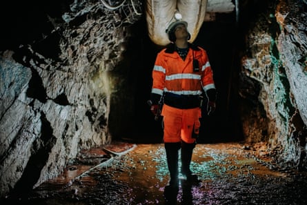 A figure in hi-vis and hard hat walking underground in a cave