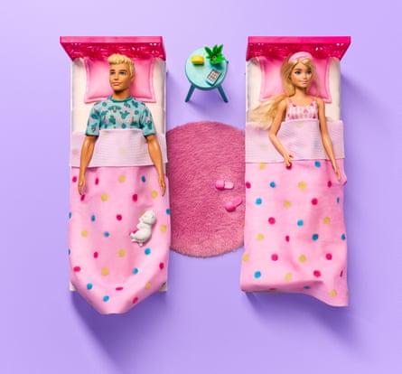 Barbie and Ken dolls in single beds with pink bedding and a pink rug between them