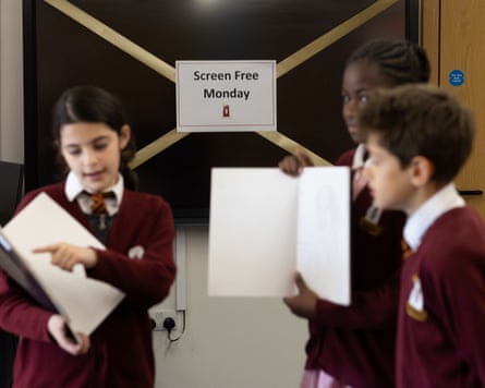 Three pupils stand in front of a monitor with tape across it and a sign that says ‘screen free Monday’