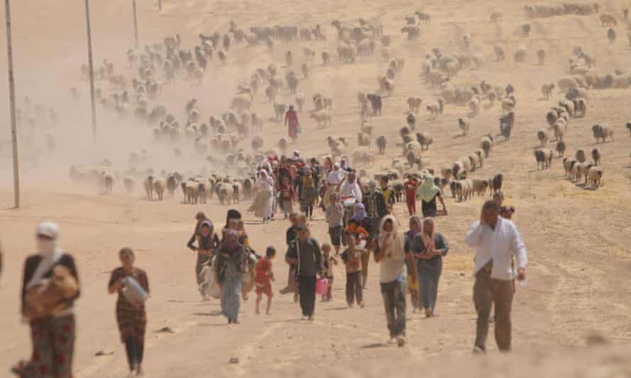 Displaced people from the Yazidi community walk towards the Syrian border on the outskirts of Sinjar mountain.
