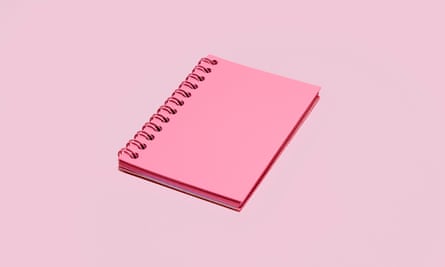 A pink spiral notebook on a pale pink background.