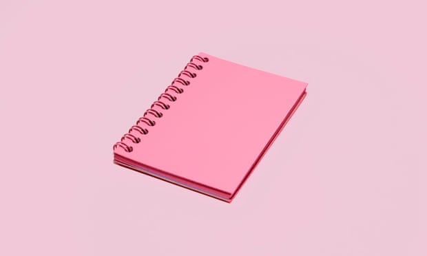 A pink spiral notebook on a pale pink background.