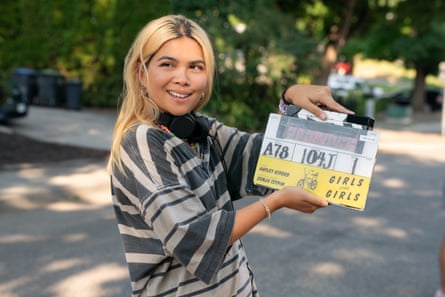 A woman standing with a film clapperboard.