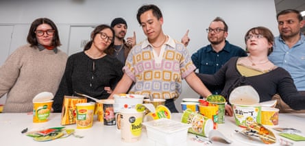 Guardian staff surround Bertin Huynh in the manner of Leonardo’s painting The Last Supper as he looks at packets of noodles