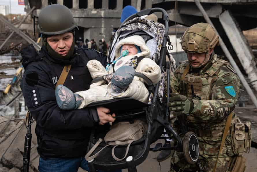 Servicemen carry a baby to safety as the UN refugee agency UNHCR estimates the total number of Ukrainian refugees at 2.1 to 2.2 million.