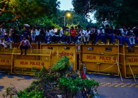 Protesters climb a police barricade