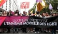 People march in a line holding a long banner in front of them that reads: 'L'extrême droite est l'ennemie mortelle des LGBTI'