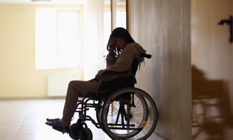 Woman in wheelchair and holding her head in clinic