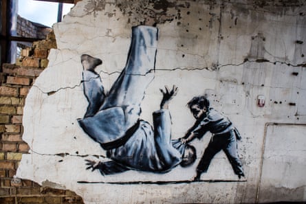 Banksy mural showing a child wrestler felling a large man on a ruined wall in Borodianka, Ukraine