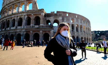 A tourist wearing a protective respiratory mask tours outside the in Rome, 28 February.