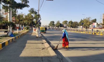 Donna che spazza la strada tranquilla sotto il cielo azzurro