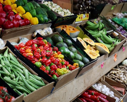 A supermarket display holds crates of colourful peppers, bananas, avocados, squash and okra