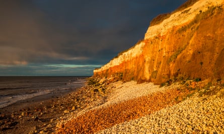 Hunstanton Cliffs at sunset with dark stormy sky, on Norfolk coast, where white chalk overlays red limestone in a colorful formation. England, UK.Hunstanton Cliffs at sunset with dark stormy sky, on Norfolk coast, where white chalk overlays red limestone in a colourful formation. England, UK.