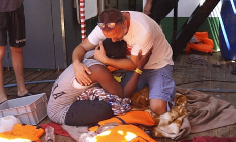 A crew member of the Open Arms humanitarian boat comforts a person rescued from the sea.