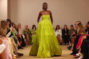 A model in a floor length, chartreuse-green dress walks the runway at Aje.