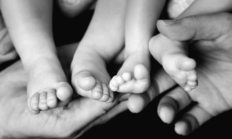 Tiny baby twins' feet in parents' hands