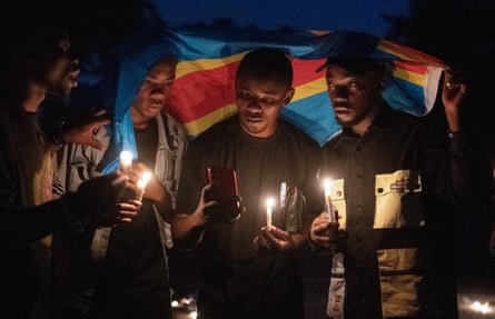 People stand in a circle holding burning candles. 