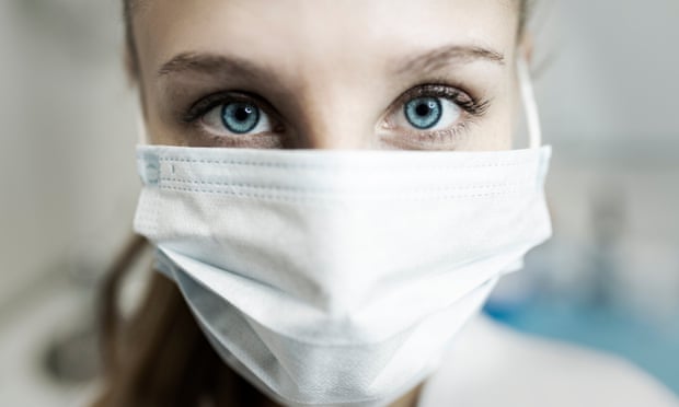 Blue-eyed nurse at her workplace wearing a protective mask.