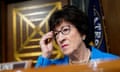 Woman wearing blue suit adjusts glasses