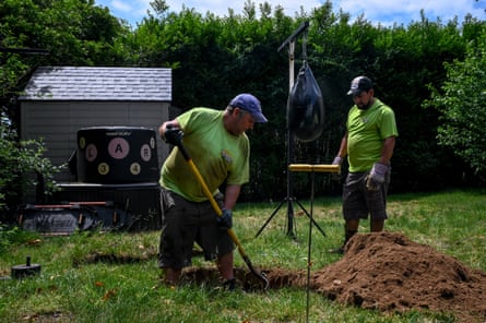 Employees at Emil Norsic and Son, Inc., Michael McCallen (left), 47, and Isidro Arellanos (right), 39, dig up a cesspool cover after receiving an emergency call from a resident experiencing sewage backup on Thursday, June 10, 2021 in the Sag Harbor village of Southampton, New York. Without a public sanitation department, residents of Southampton mainly rely on private businesses, such as Emil Norsic and Son, Inc., to handle sewage problems.