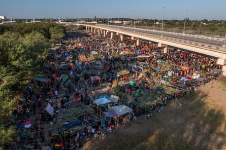 Migrants await to be processed along the Del Rio international bridge after crossing the Rio Grande river into the US on Sunday.