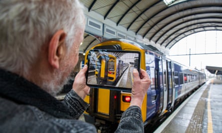 Ian Brown holds up a tablet to take a photo of the train