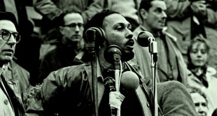 A still from Akomfrah’s 2013 film The Stuart Hall Project. Stuart Hall speaking at a microphone surrounded by other people.