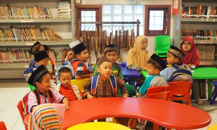 Indonesian children in a colourful classroom surrounded by bookshelves.